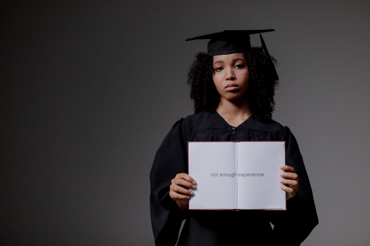about-us Young graduate holding a book with 'not enough experience' message, symbolizing job hunt difficulties.